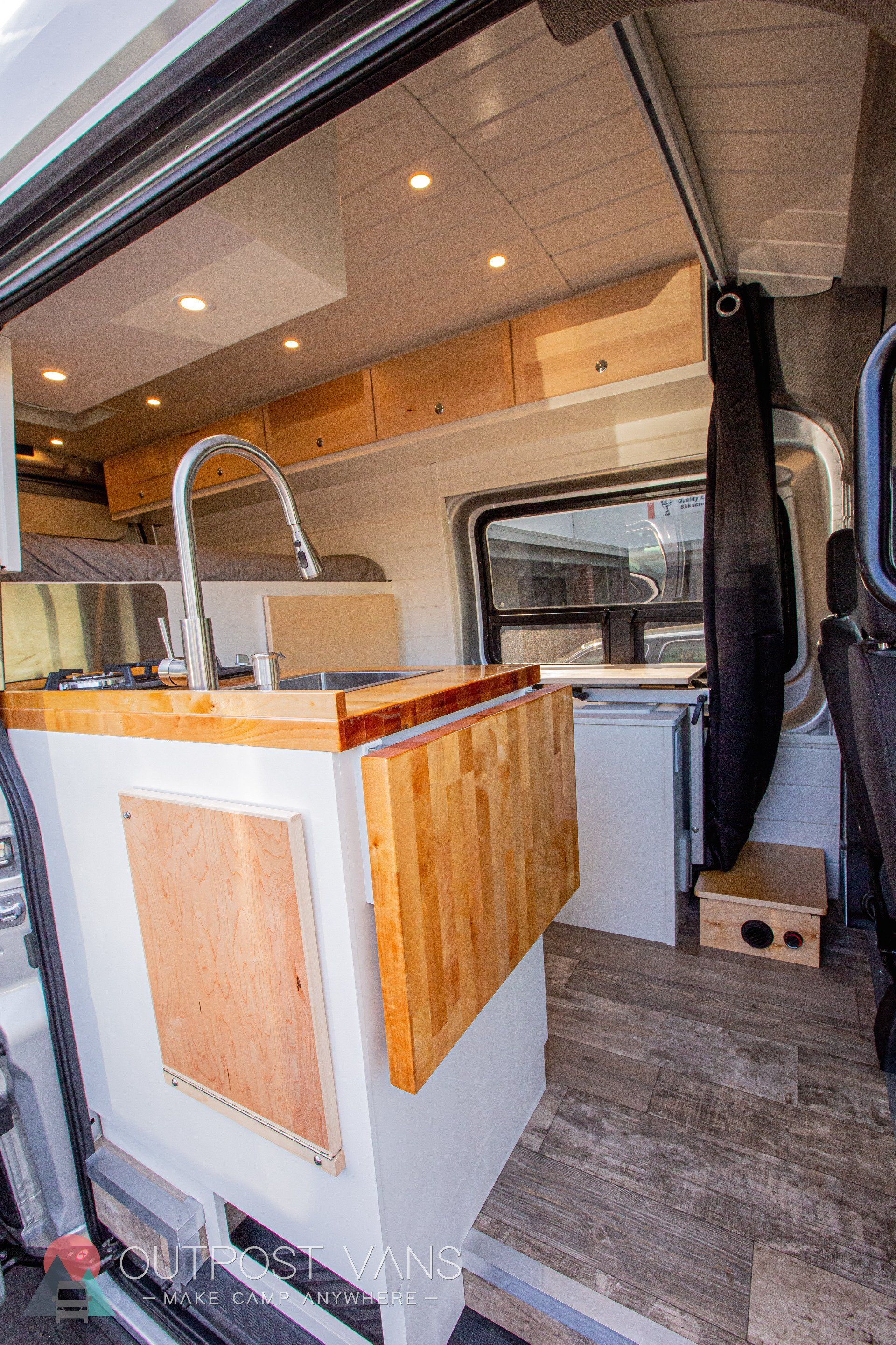 a kitchen in the back of a van with a sink and a table .