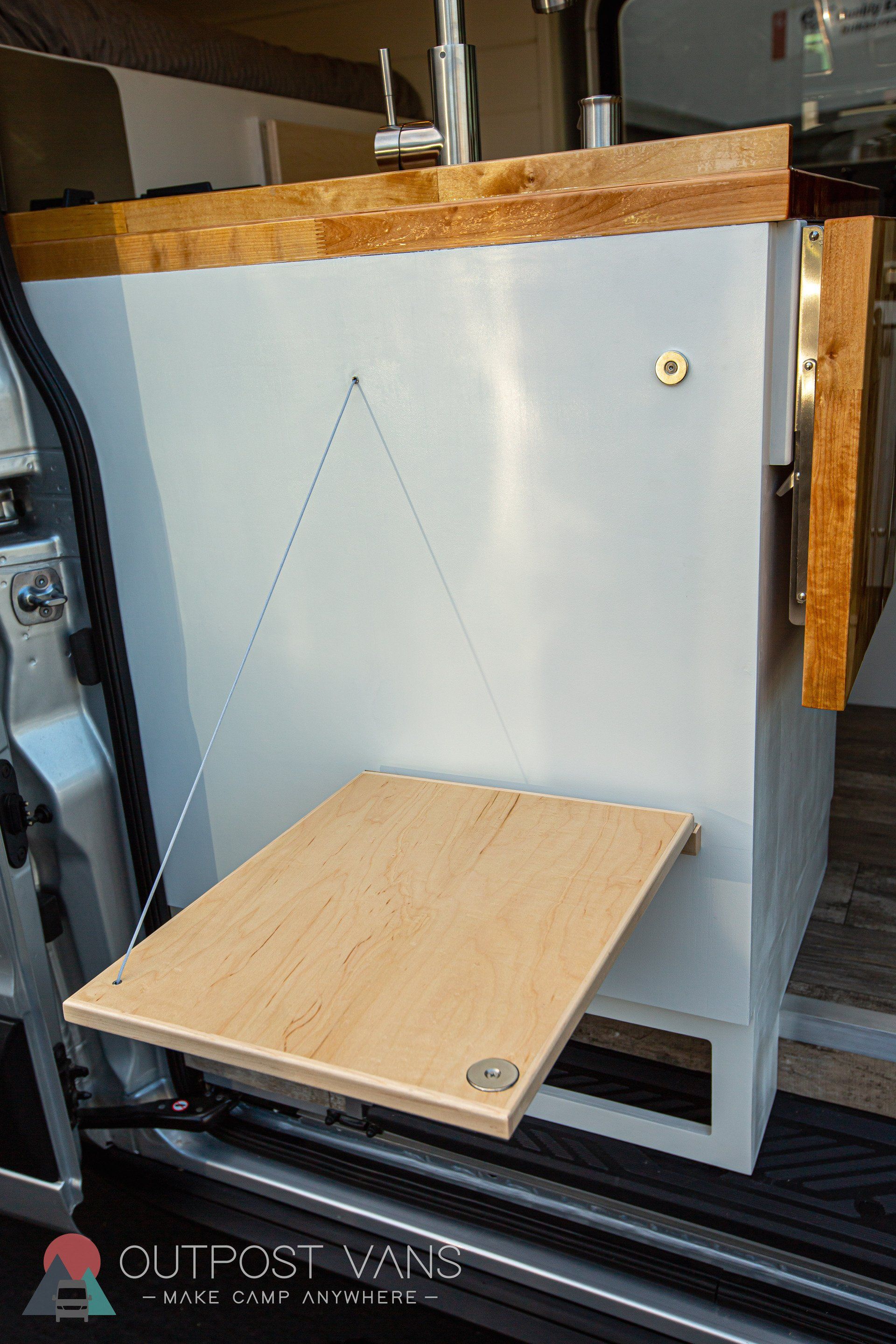 a wooden table is attached to the side of a van .