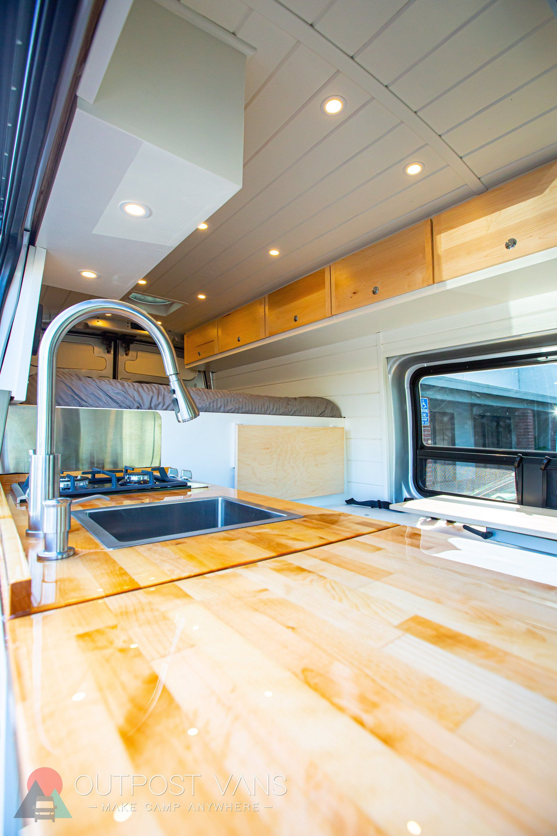 a kitchen in a van with wooden counter tops and a sink .