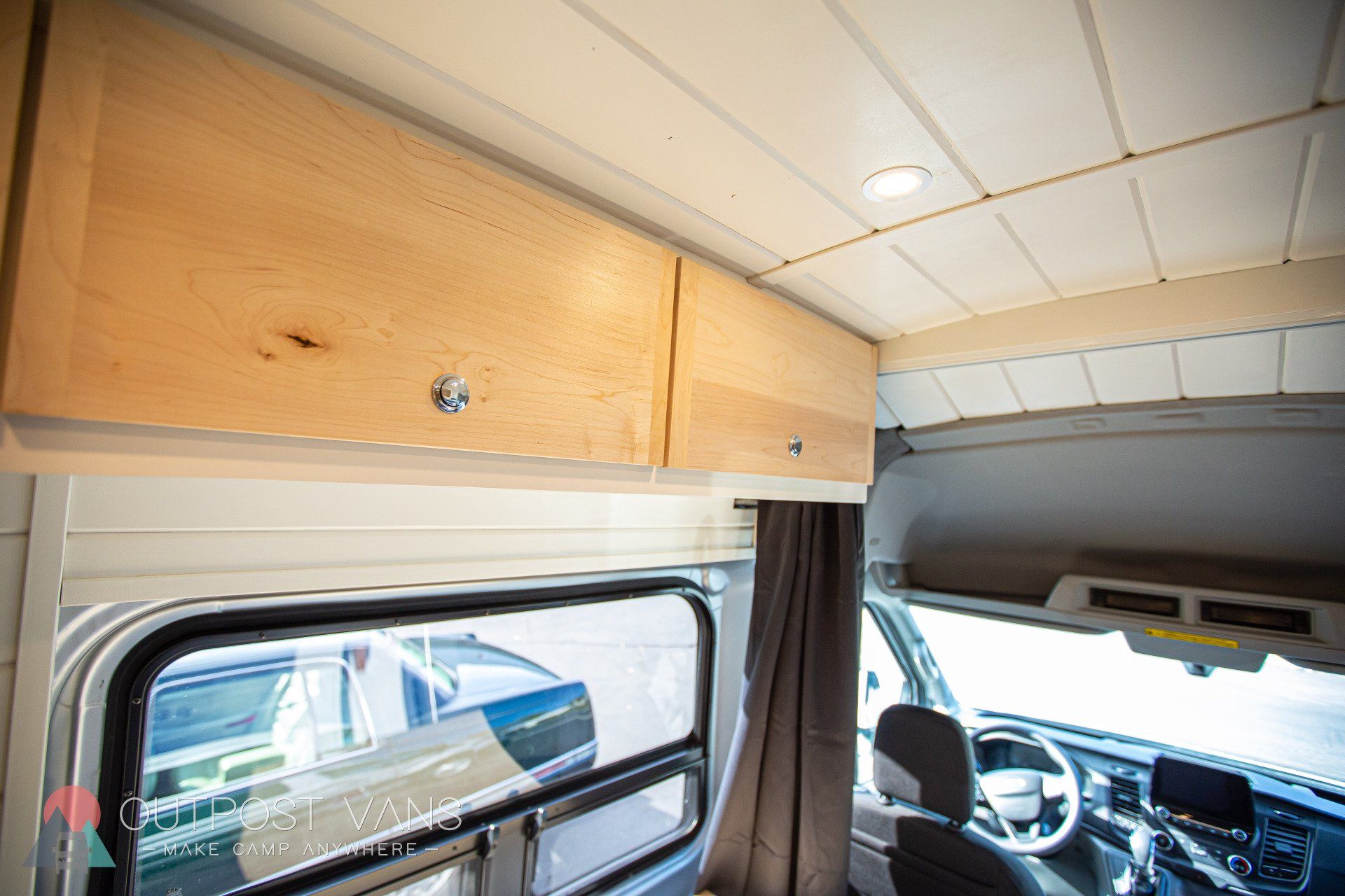 the inside of a van with wooden cabinets and a window .