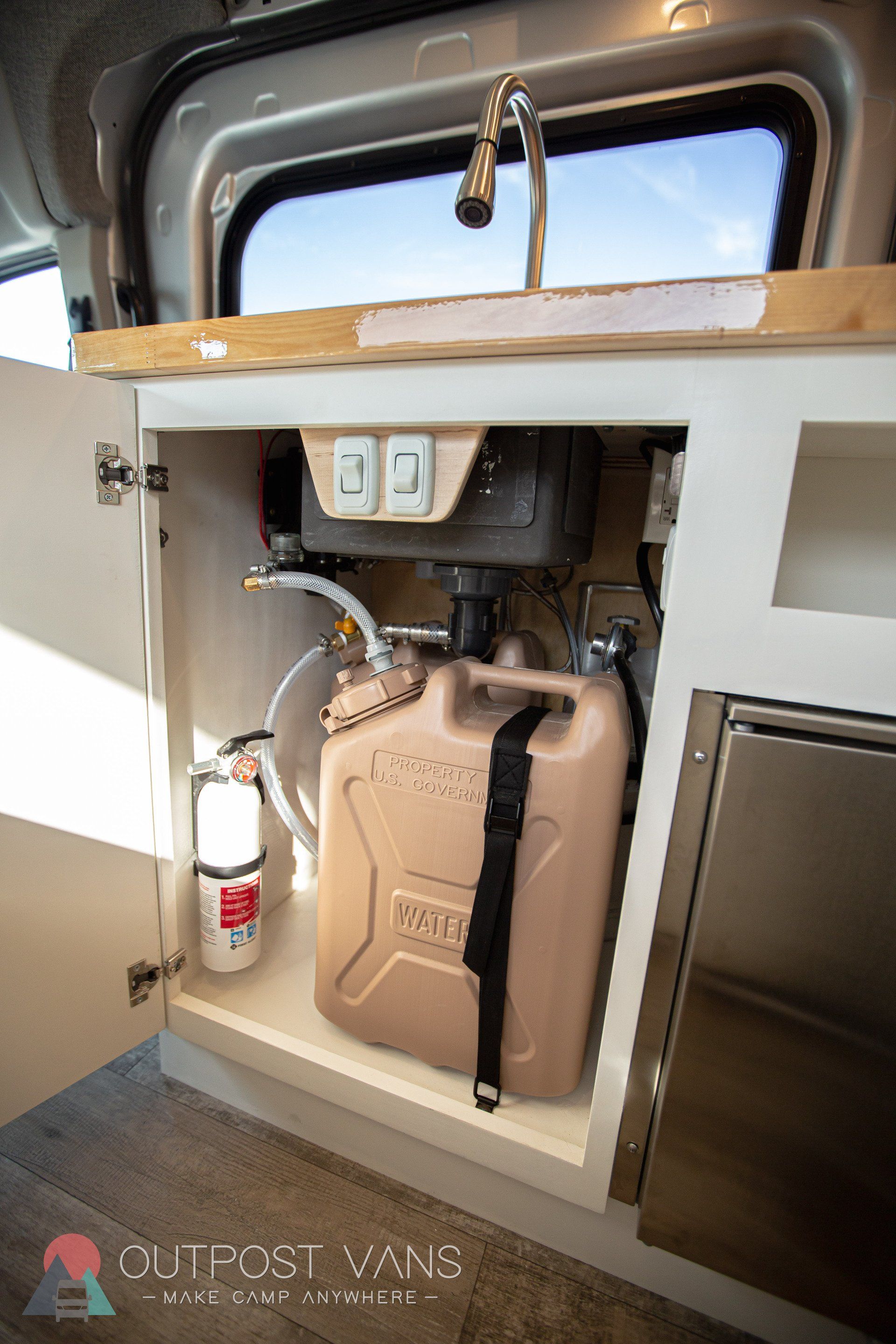 a jerry can is sitting under a sink in a van .