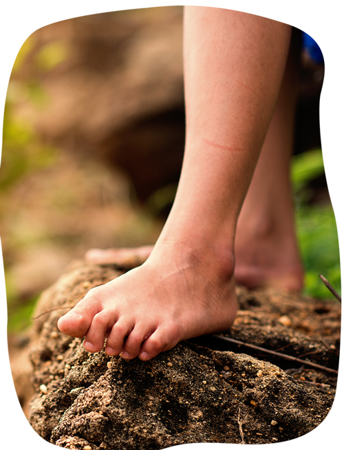 A child 's bare feet are standing on a rock