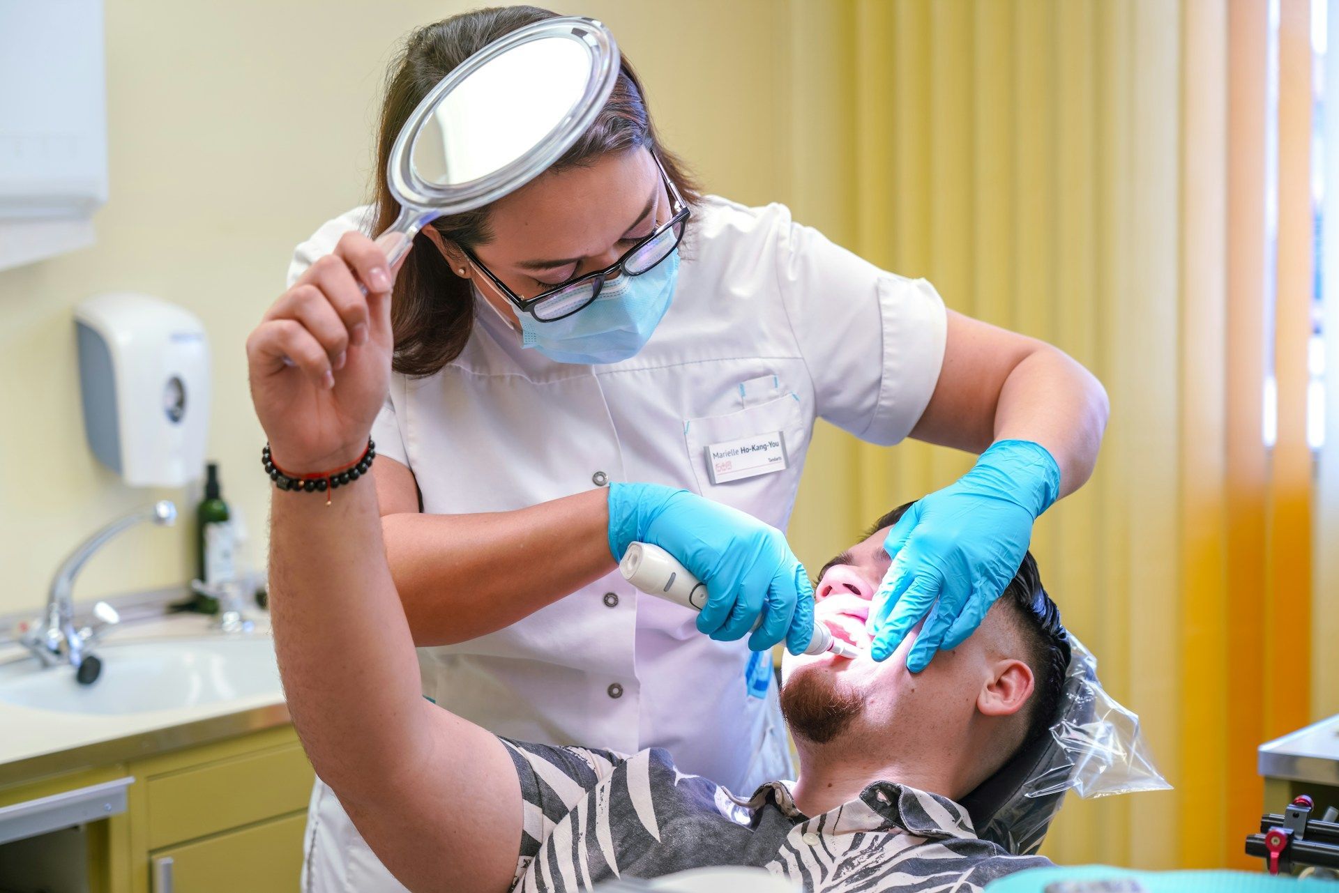 A dentist is performing a deep cleaning on a man's teeth in a dental office.