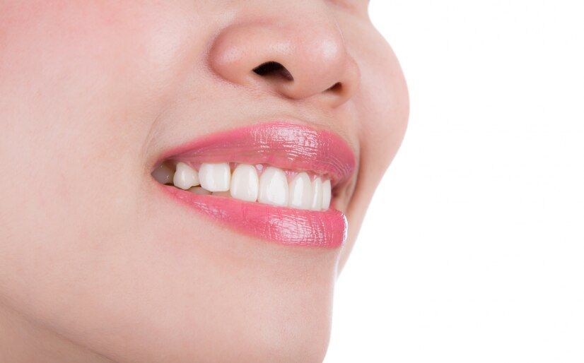 A close up of a woman 's mouth with white teeth and pink lipstick.