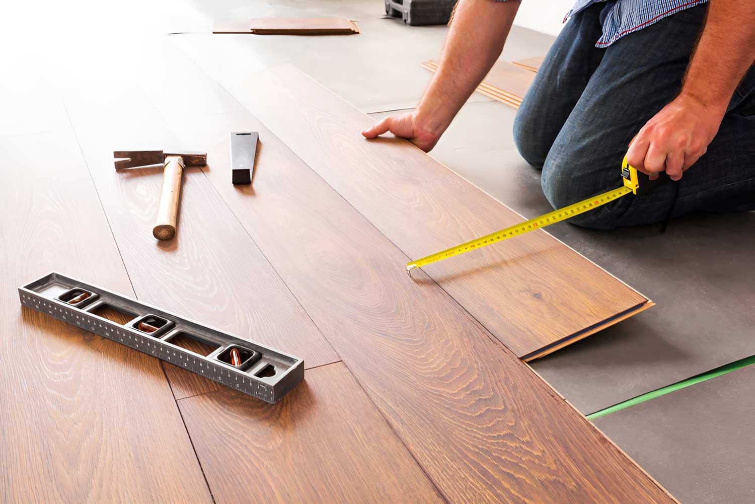 Man Installing New Laminated Wooden Floor — Flooring Direct Mid North Coast in  Kempsey, NSW