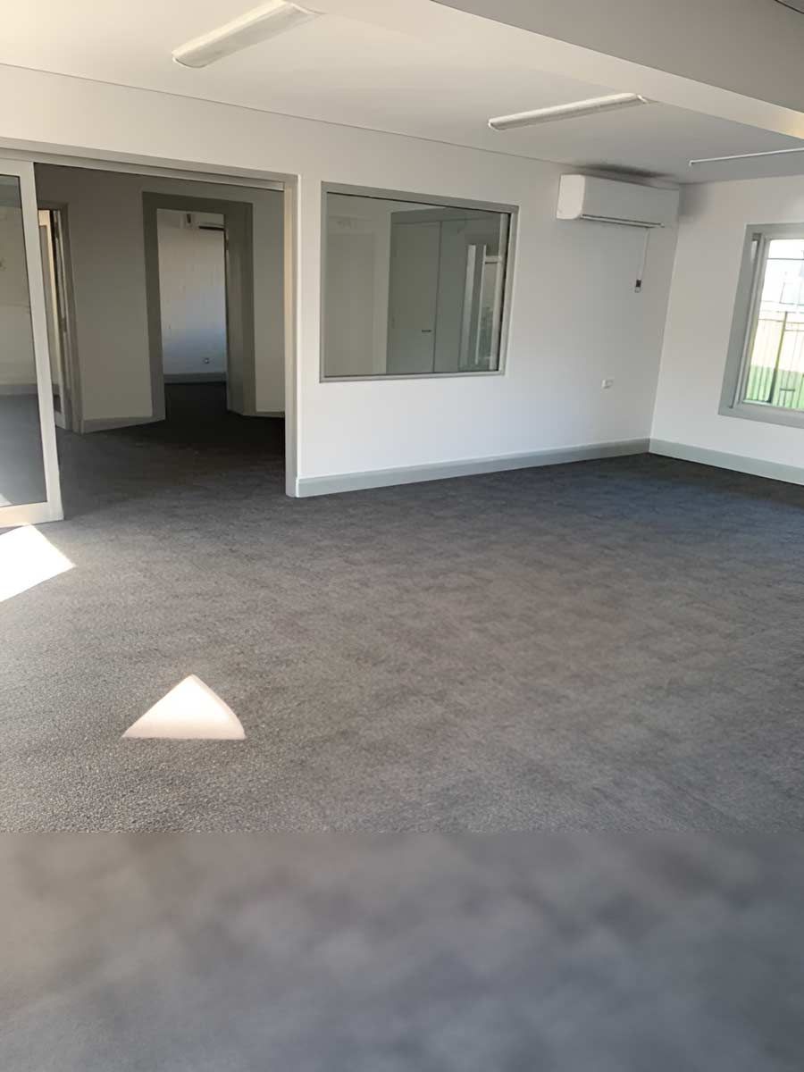 A Spacious, Empty Room With A Gray Carpet — Flooring Direct Mid North Coast in Macksville, NSW