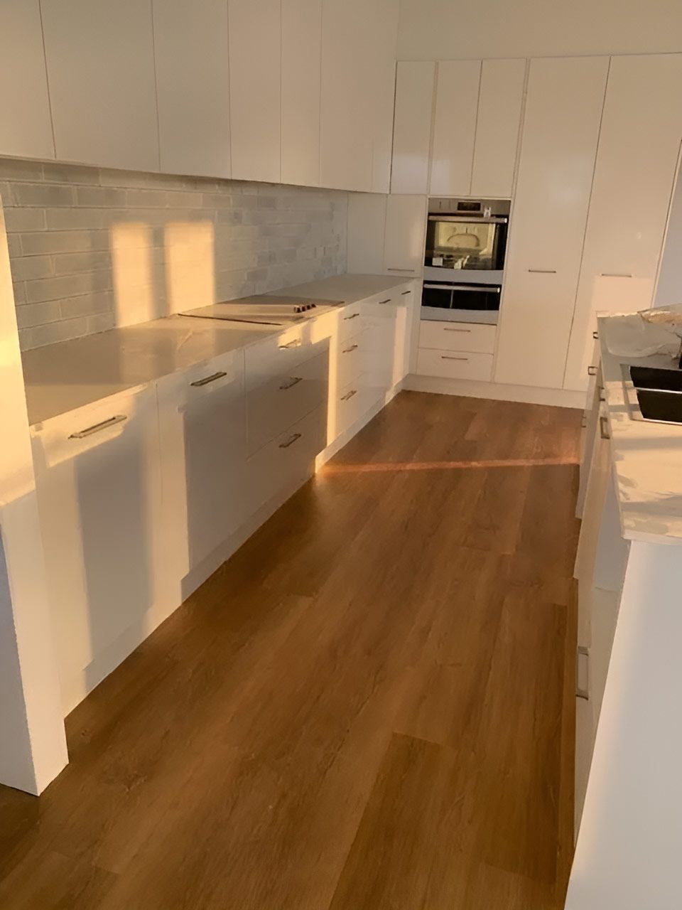 A Kitchen Featuring White Cabinets And Wooden Flooring — Flooring Direct Mid North Coast in South Kempsey, NSW
