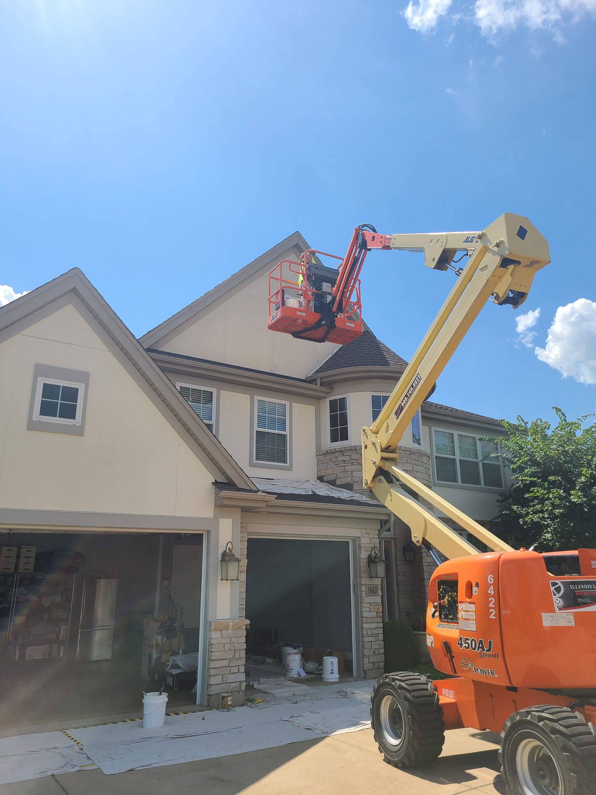 A large house is being painted by a crane.