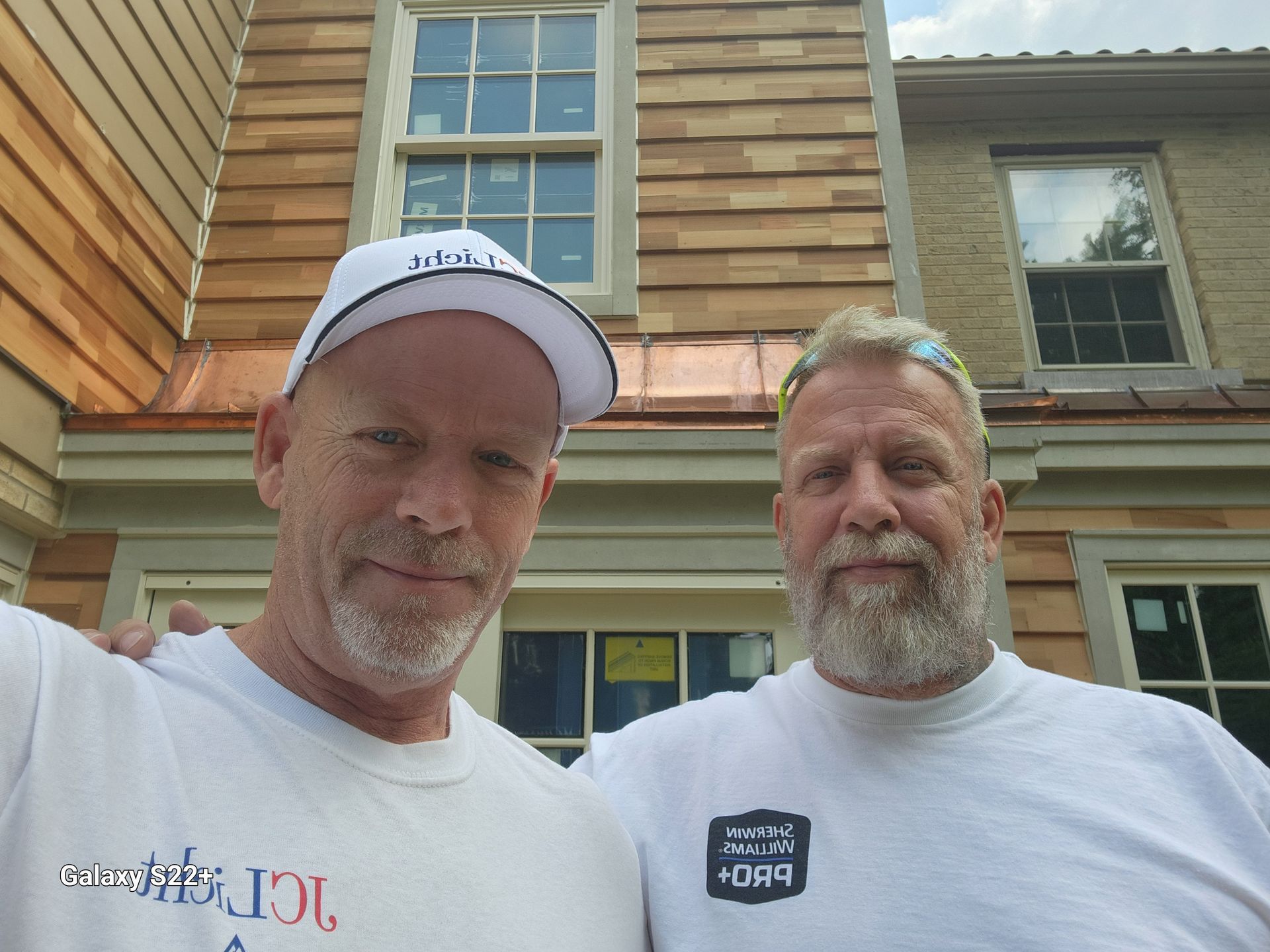 Two men are posing for a picture in front of a house