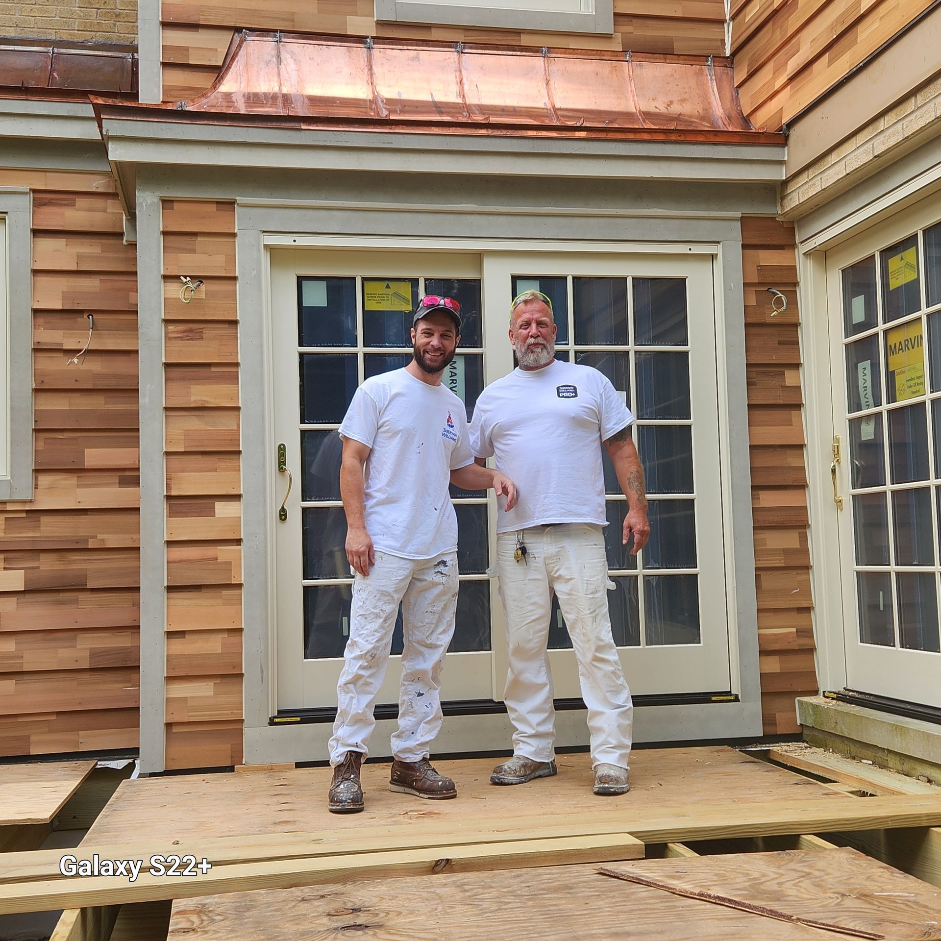 Two men standing in front of a house with a copper roof