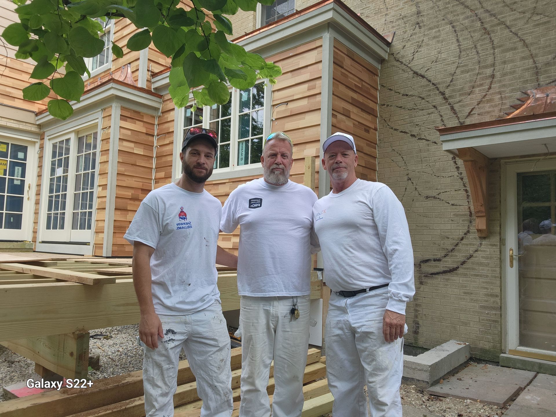 Three men are posing for a picture in front of a house.