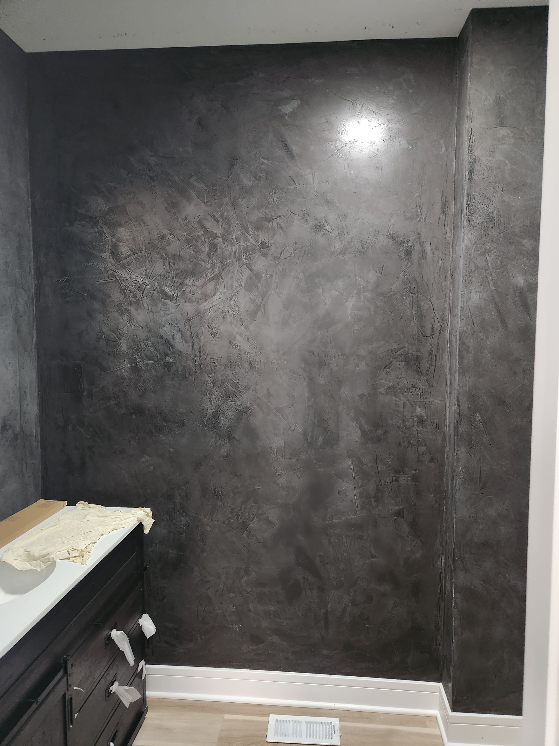 A bathroom with a black wall and a sink.