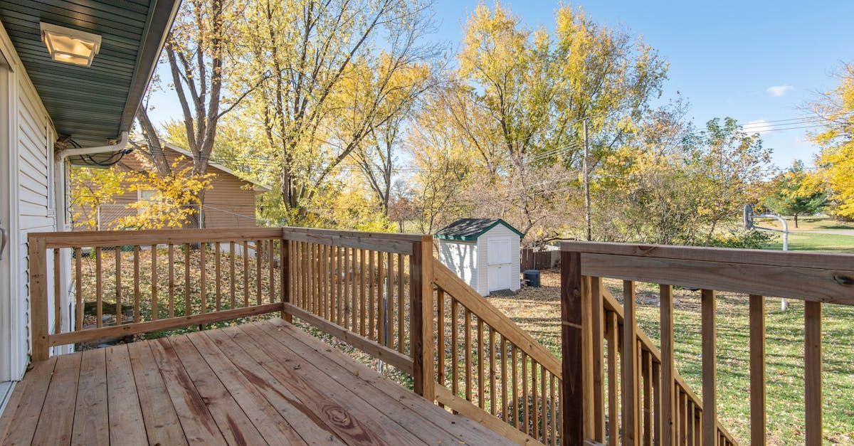 A wooden deck with stairs leading up to it and trees in the background.