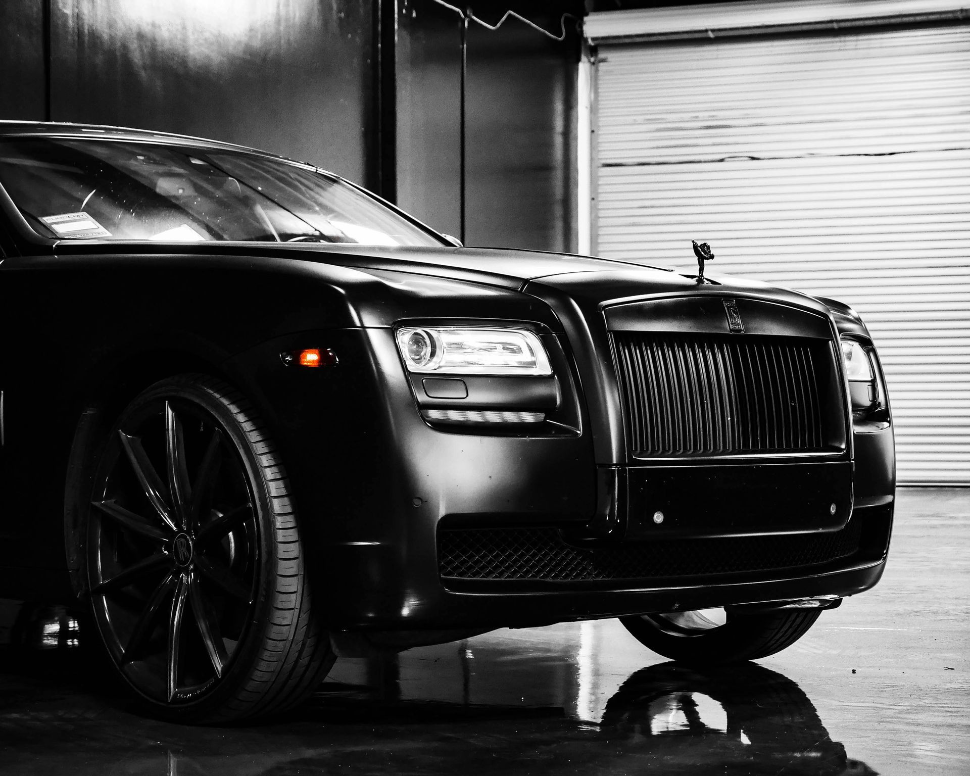 A black and white photo of a rolls royce parked in a garage