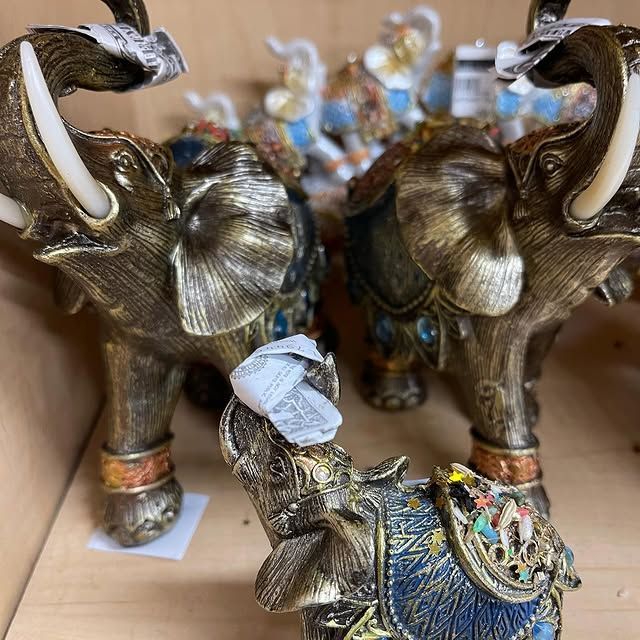 Close-up of decorative elephant figurines in various colors, some with ornate details, on a shelf.