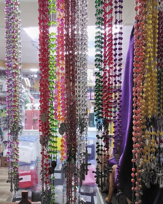 Rows of colorful rosaries hanging in a store, viewed from an interior perspective.