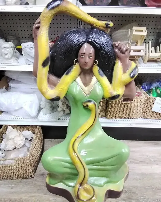 Statue of a woman in green, with a yellow snake coiled around her.