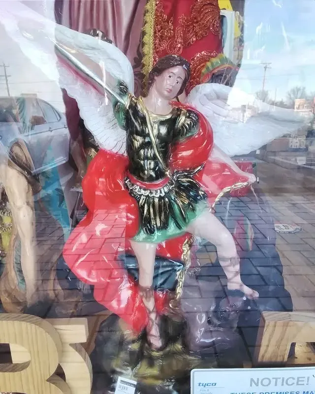 Statue of Archangel Michael with sword and white wings, wearing red, green, and gold armor.