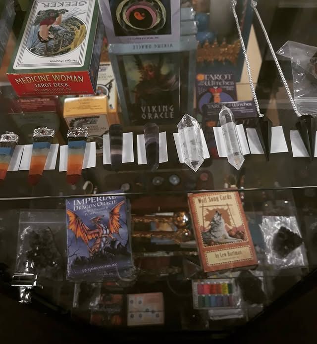 Tarot decks, crystals, and other mystical items arranged on a glass surface.