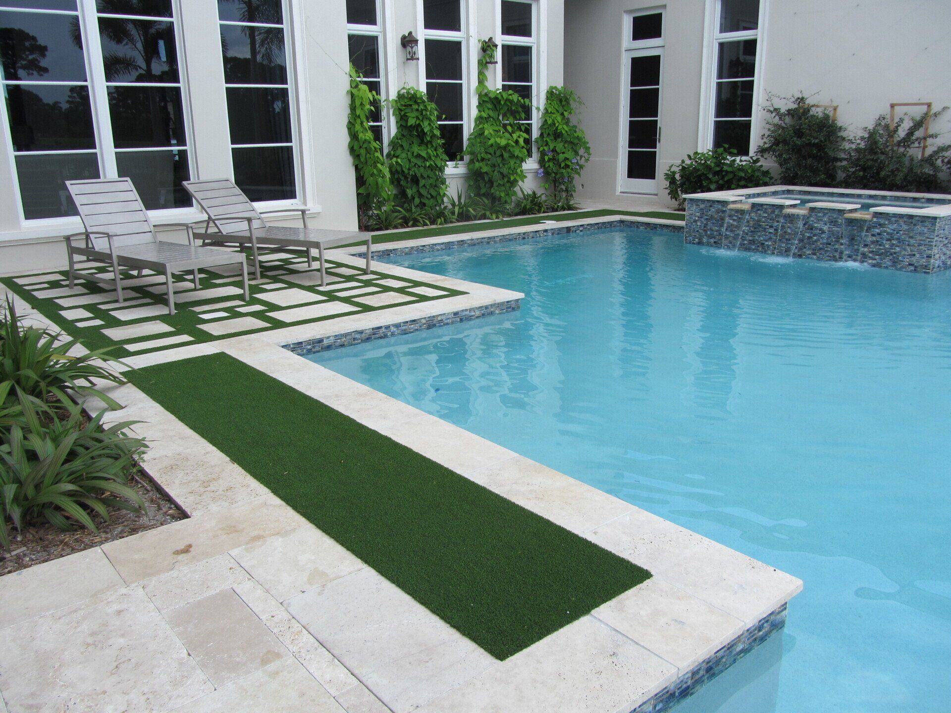 Swimming pool with artificial turf walkway and seating area.