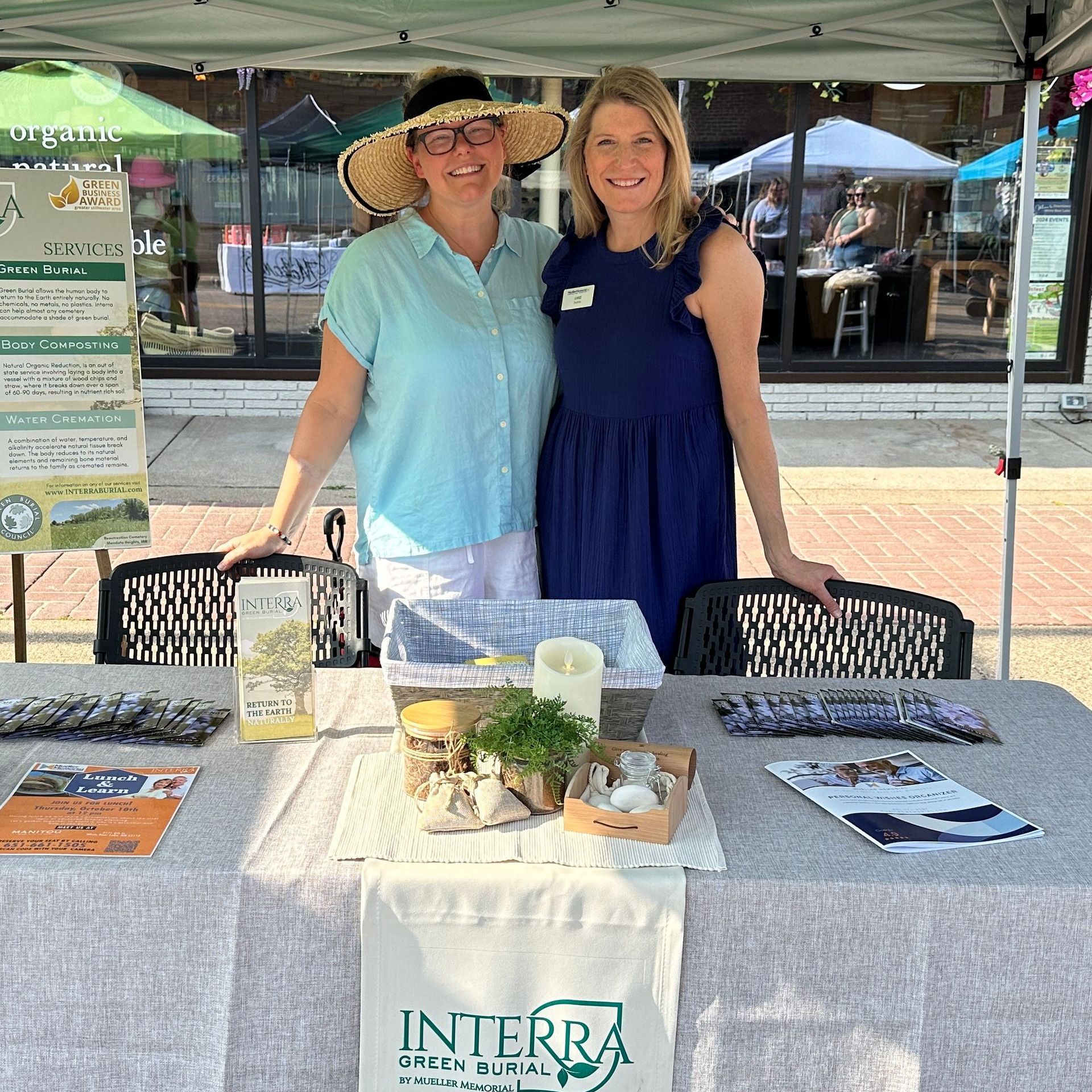 Two women standing at a festival booth for Interra Green Burial