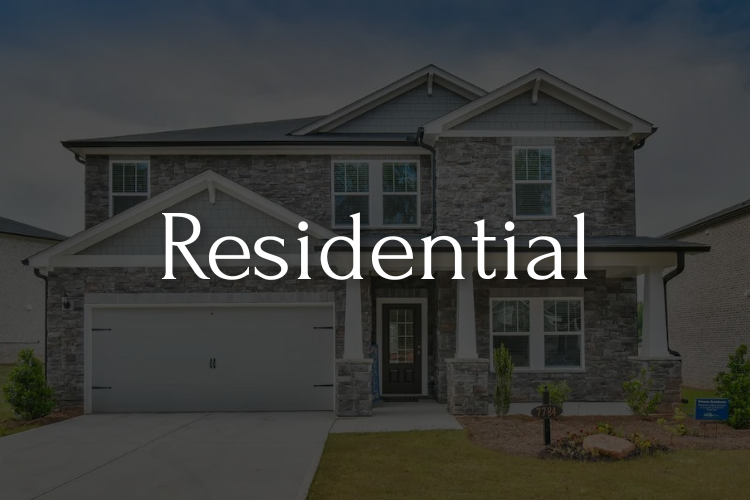 A two-story residential home with a gray stone facade. The word 