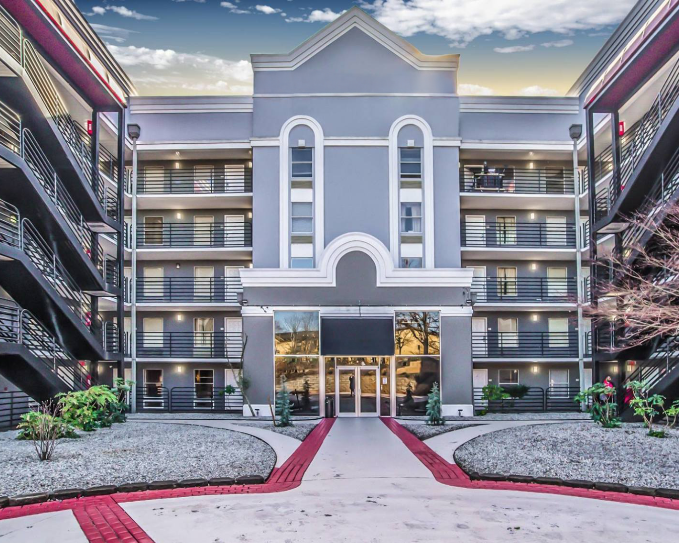 Buildings with brick facades and storefronts, cars parked in front.