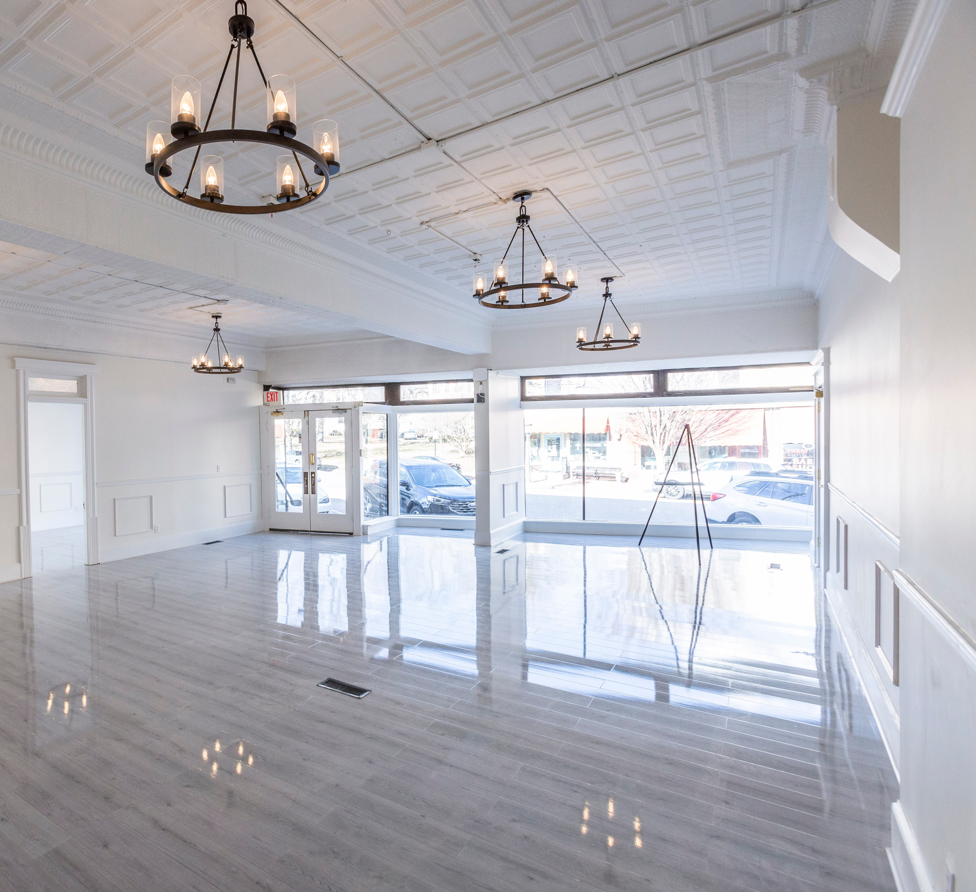 Buildings with brick facades and storefronts, cars parked in front.