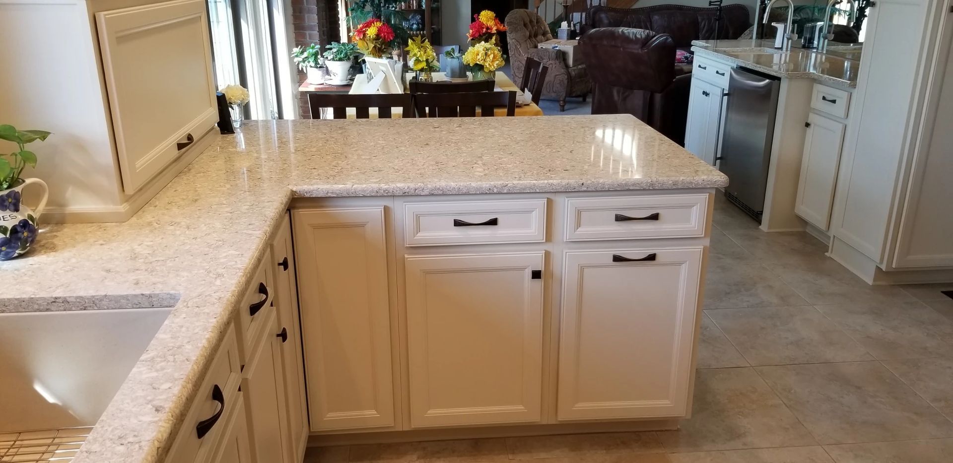 Kitchen with light granite countertops and white cabinets. Black hardware is on the drawers.