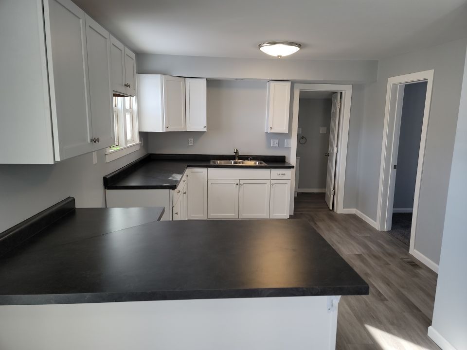 Kitchen with white cabinets, dark countertops, and gray walls.