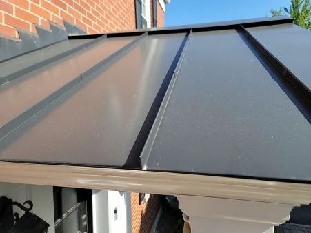 Black metal awning over a white trim doorway, attached to a brick building.