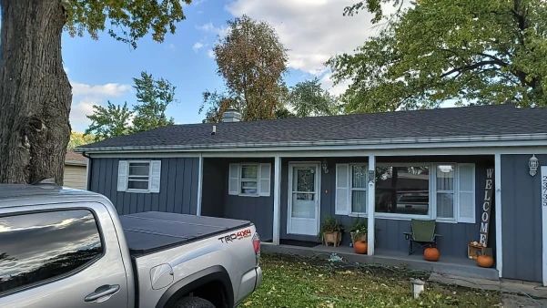 Blue house with white trim, a covered porch, and a gray pickup truck parked in front.