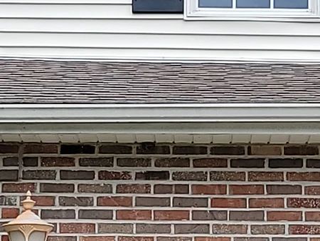 Close-up of a house exterior with brick, siding, and roofing materials.