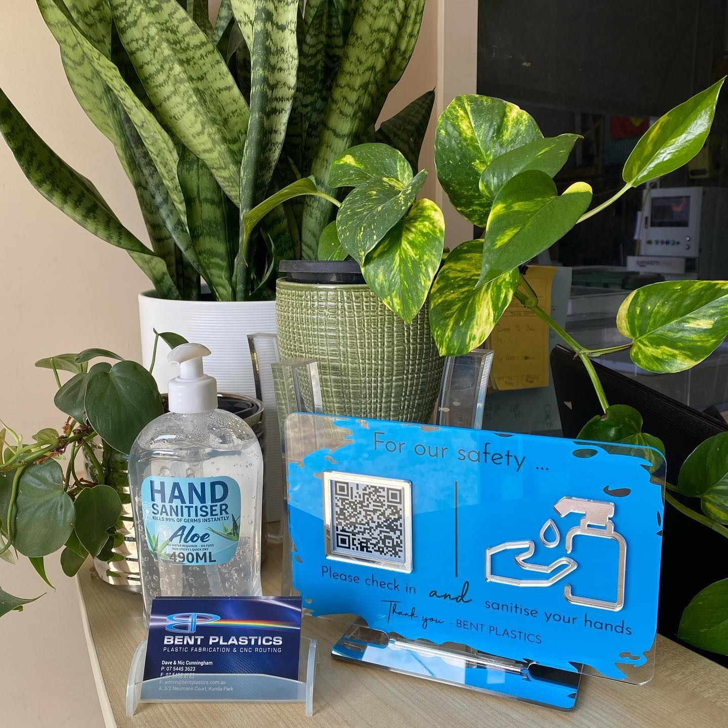 A Bottle of Hand Sanitizer Sits on a Table Next to Some Plants — Bent Plastics in Kunda Park, QLD