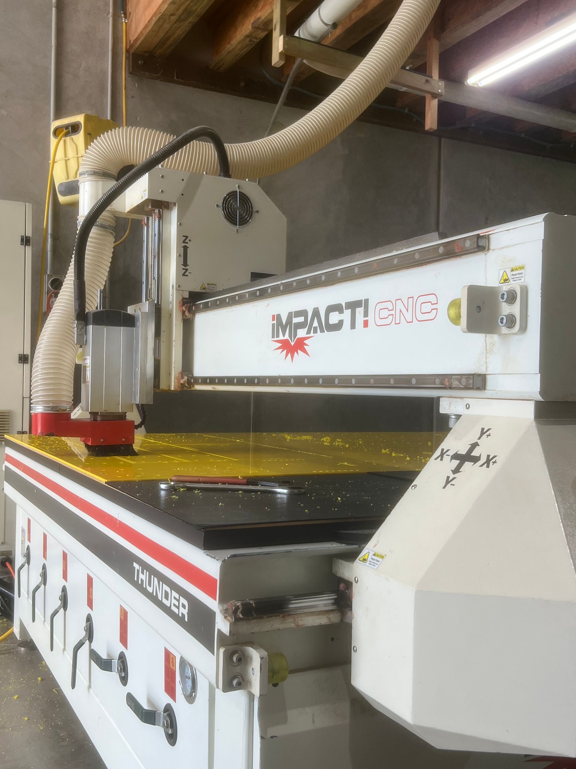 CNC router machine, white and red, in a workshop. Dust collection hose is attached — Bent Plastics in Kunda Park, QLD