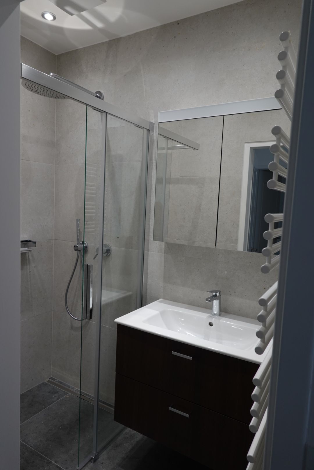 Ein Badezimmer mit Waschbecken, Spiegel und Duschkabine.