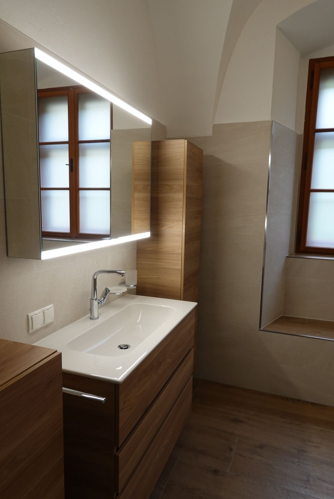 Ein Badezimmer mit Waschbecken, Spiegel und Fenster