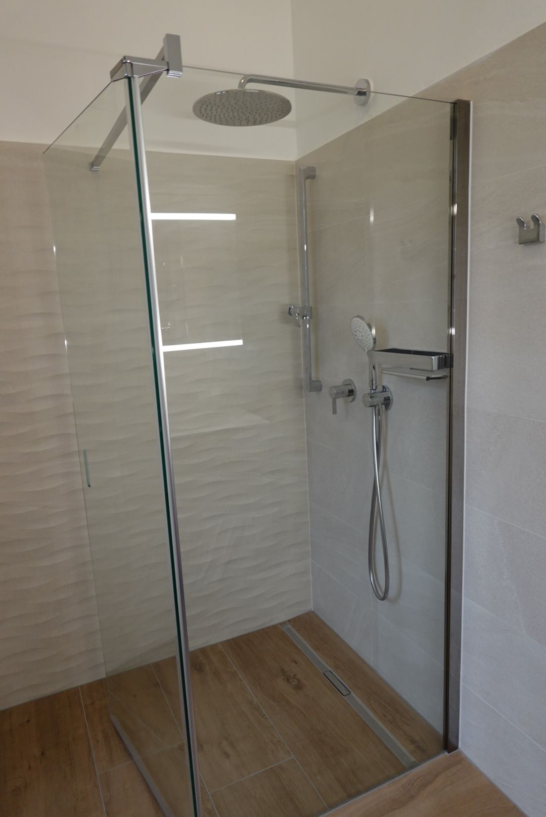 Eine ebenerdige Dusche mit Glastür und Duschkopf.