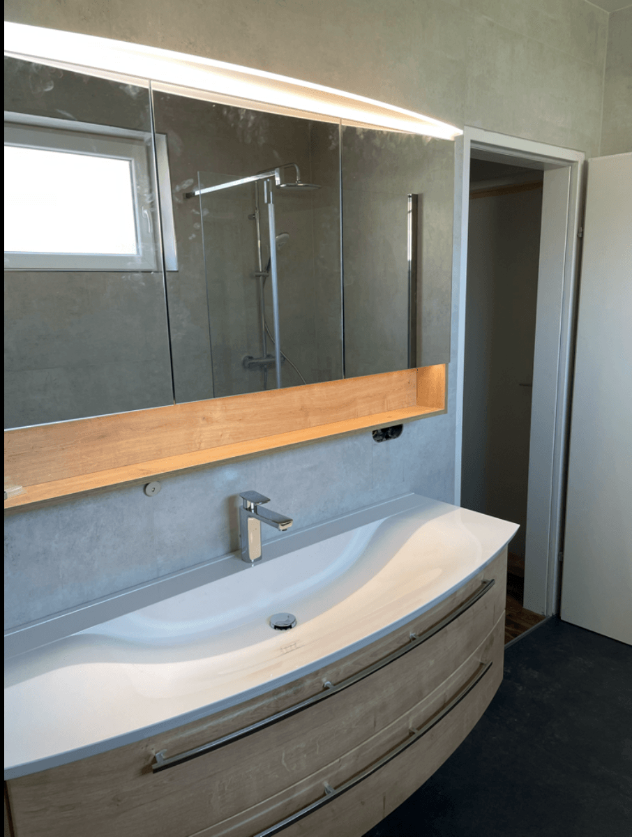 Ein Badezimmer mit Waschbecken und großem Spiegel