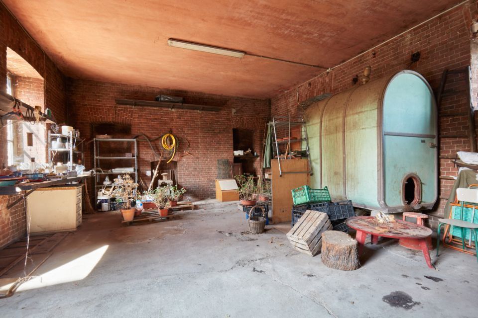 Un laboratorio disordinato con pareti in mattoni e un grande contenitore cilindrico.