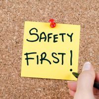 A person is writing on a yellow sticky note that says,