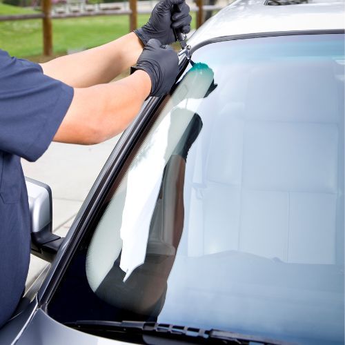 A man is fixing a windshield on a car