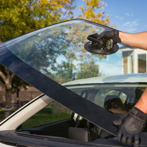 A person is installing a windshield on a car