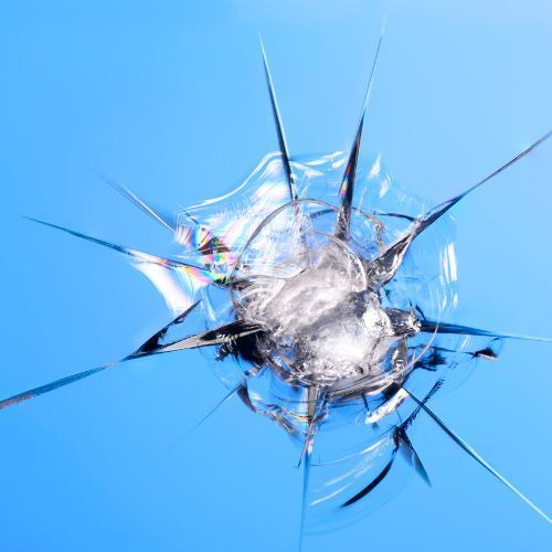 A close up of a broken windshield reflecting a blue sky.