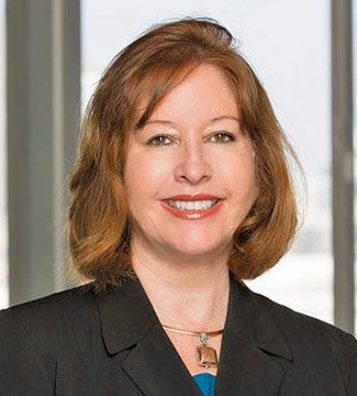 Smiling professional in a black blazer against a bright office background