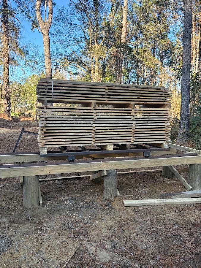 Stack of rough-hewn wooden planks, outdoors, forest background, warm tones.