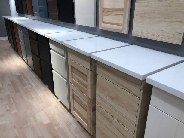 Kitchen cabinet display with various door styles, countertop samples, and wood flooring.