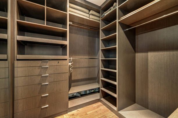 Walk-in closet with shelves, drawers, and hanging rods. Dark wood cabinetry, empty.