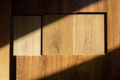 Wooden flooring samples on a wood surface, with sunlight casting shadows.
