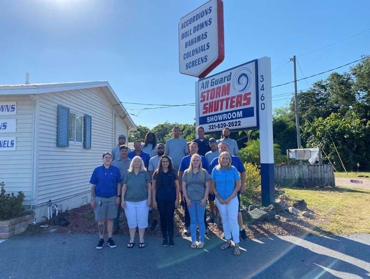 A diverse group of staff standing in front of a business sign for 